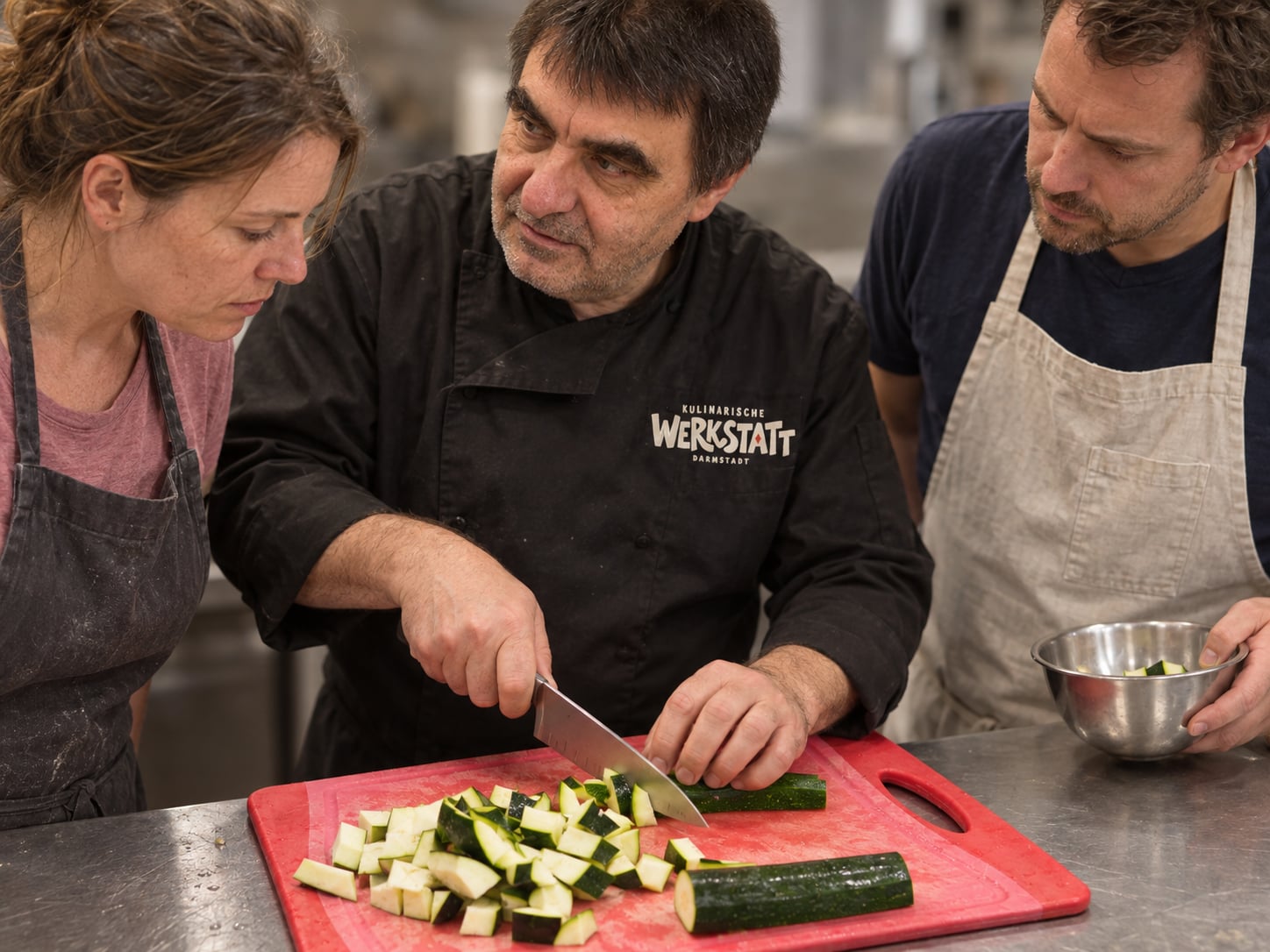 Alf erklärt zwei Teilnehmern das Schneiden von Zucchini