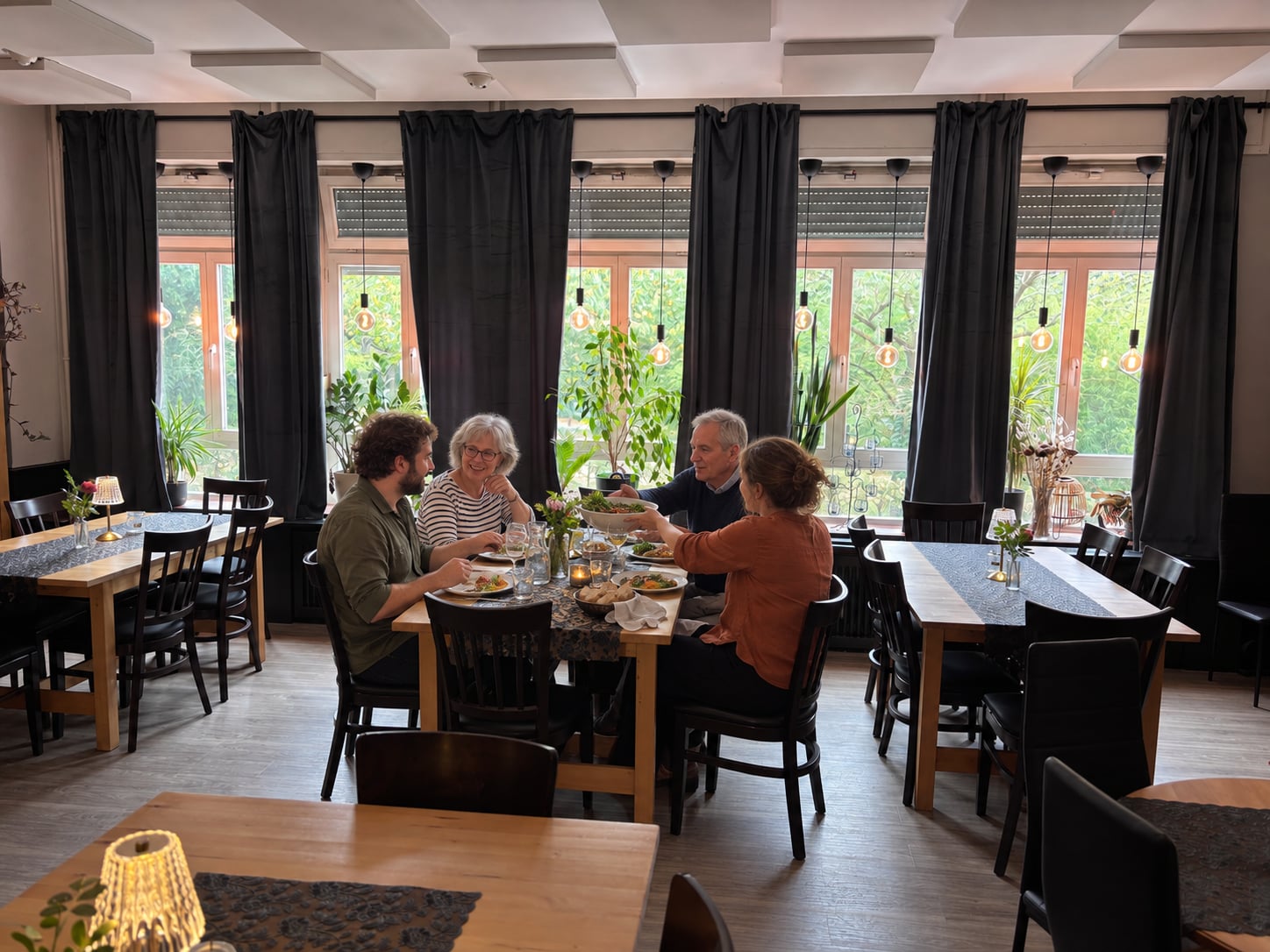 Erwachsene verschiedener Generationen essen und unterhalten sich am Fenster