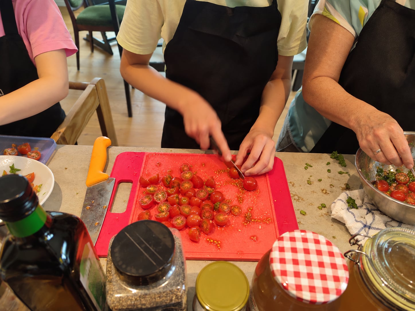 Mehrere Teilnehmer schneiden Tomaten an einer benutzten Arbeitsfläche