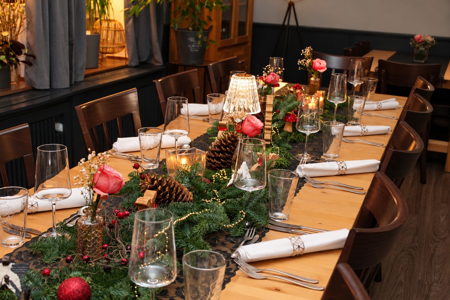 Weihnachtlich gedeckte Tafel der Kulinarischen-Werkstatt mit Tannengrün, Kerzen und Rosen
